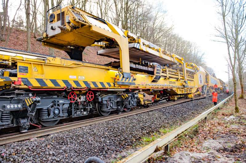 The gantry unit running at the top of the transport wagons can deliver 30 concrete sleepers at a time. Below, the RU 800 S is already collecting the old sleepers for removal. 