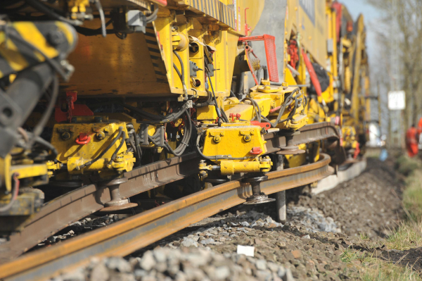 RU 800 S: Schienenführungszangen übernehmen den materialschonenden Tausch der Langschienen. Die hellere, untere ist die neue Schiene, die von den Schwellenköpfen auf die Schienenbefestigung umgelagert wird.