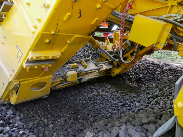 Some of the cleaned ballast is immediately sent to the area behind the excavating chain and pre-consolidated. This provides a stable ballast formation for laying new sleepers.